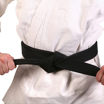 praticante de artes marciais de kimono amarrando a faixa preta
